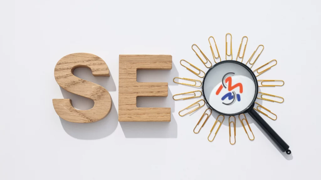 SEO spelled with wood letters and a magnifying glass for the O surrounded by paper clips with Madison Media Services logo.